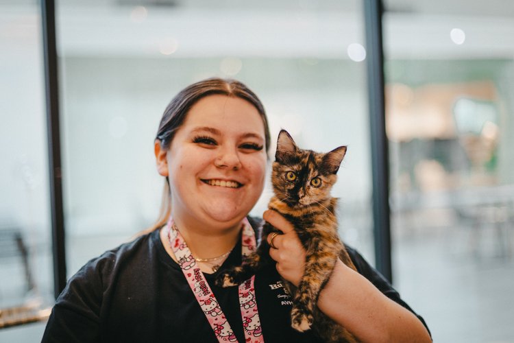 Smiling woman holding calico kitten in her arm